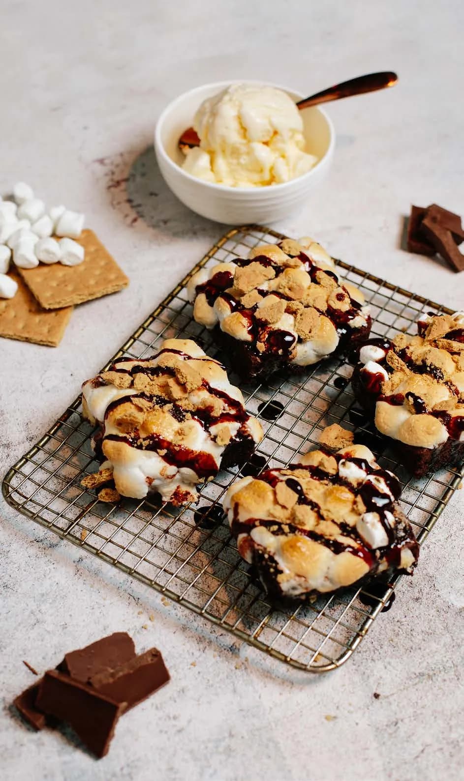 S’mores brownies topped with toasted marshmallows, graham crackers and chocolate, alongside vanilla ice cream