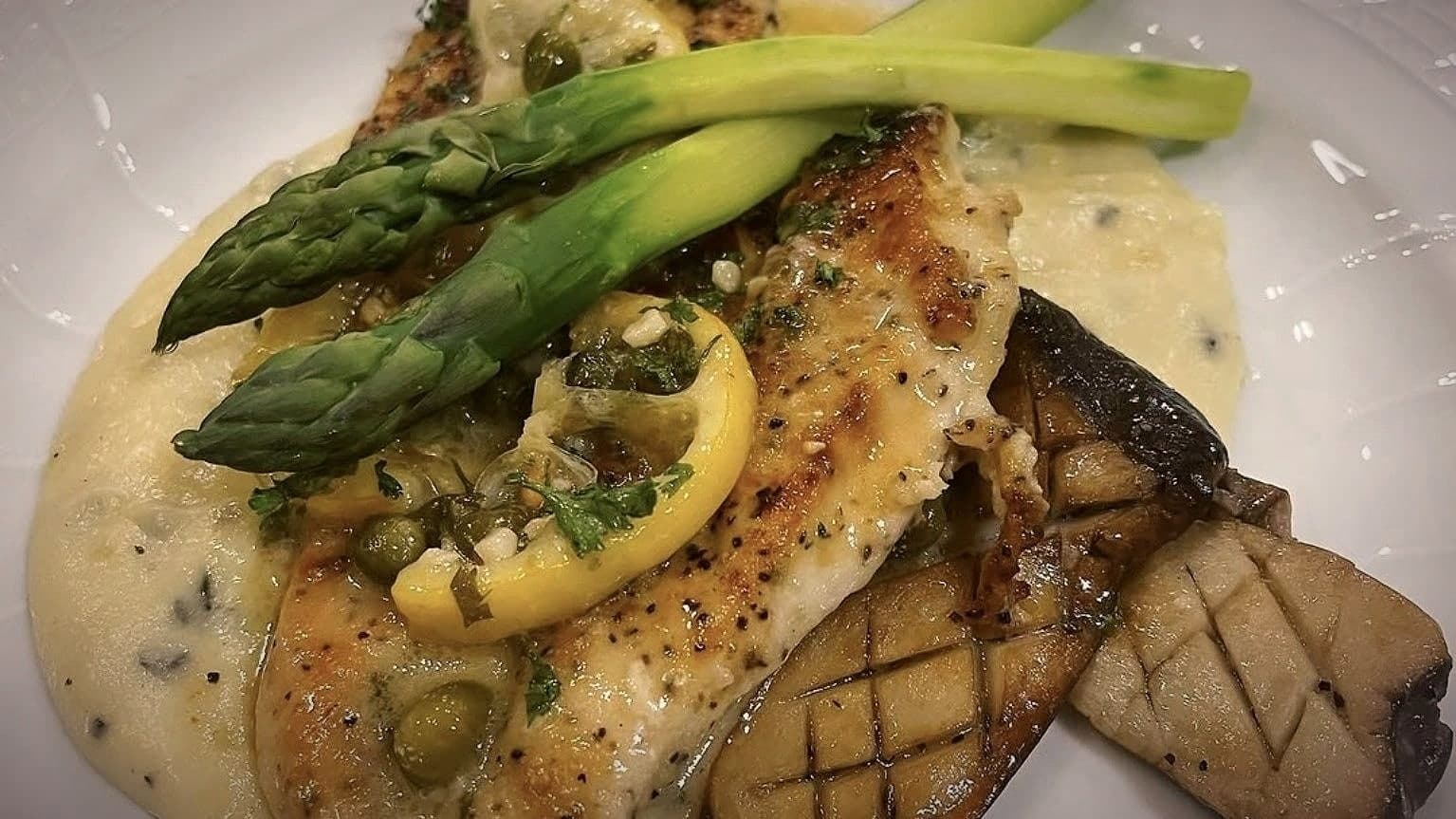 A plated dish by Chef Lauren Lawless: piccata-style fillet with lemon, capers, asparagus and king oyster mushrooms