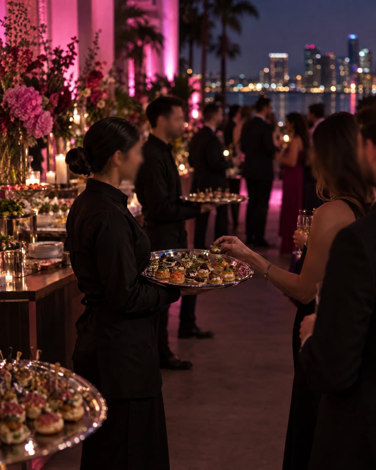 Servers passing canapes at an evening catered event